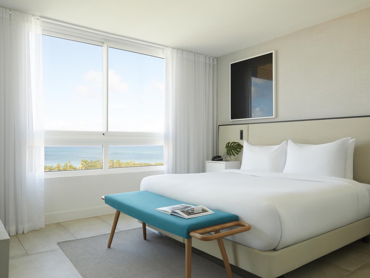 King bed with white sheets, and windows overlooking ocean