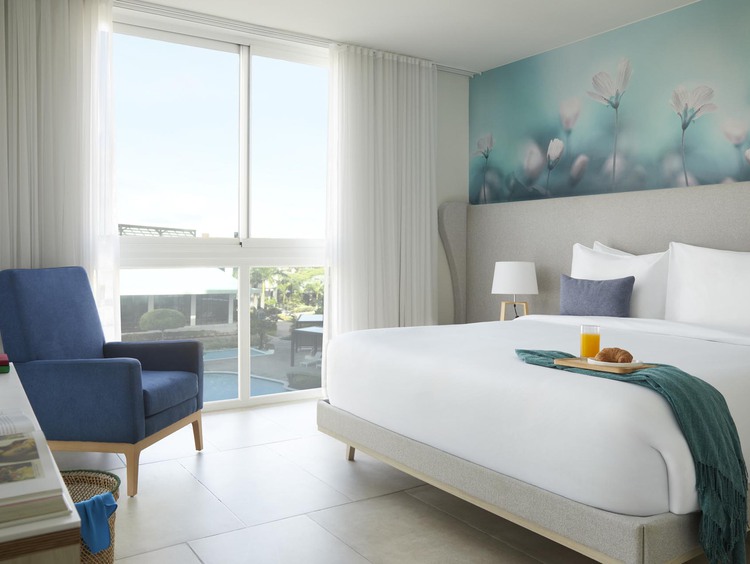 King bed with white sheets and large windows