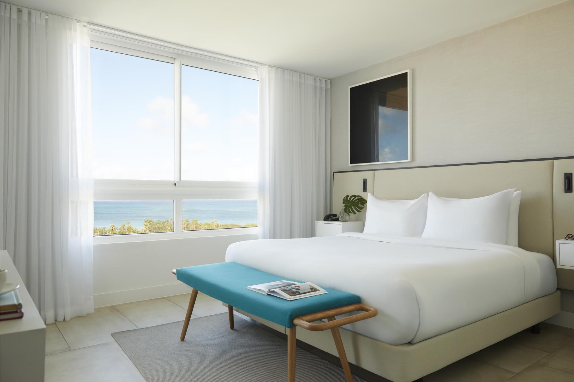 King bed with white sheets, and windows overlooking ocean