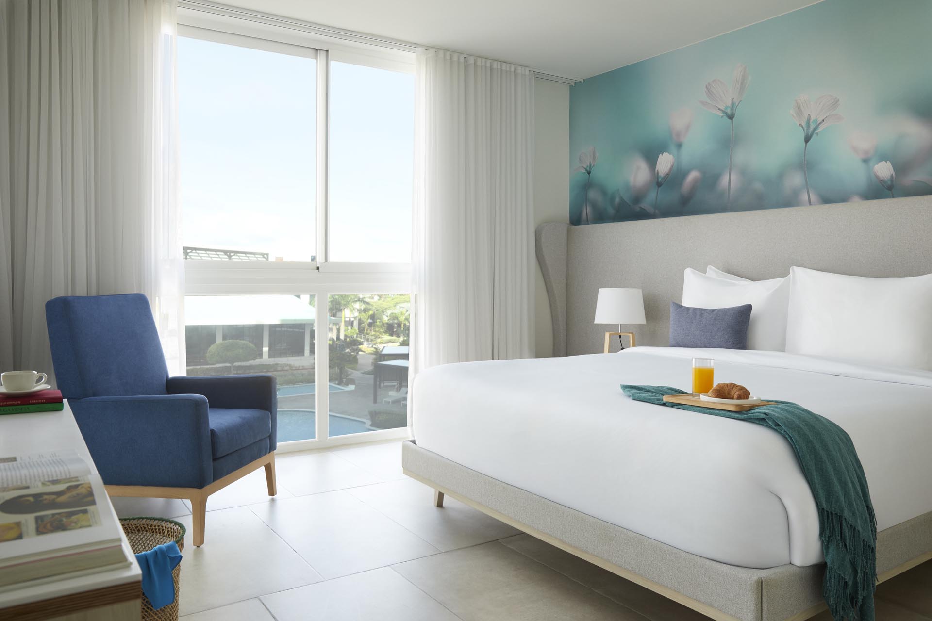 King bed with white sheets and large windows